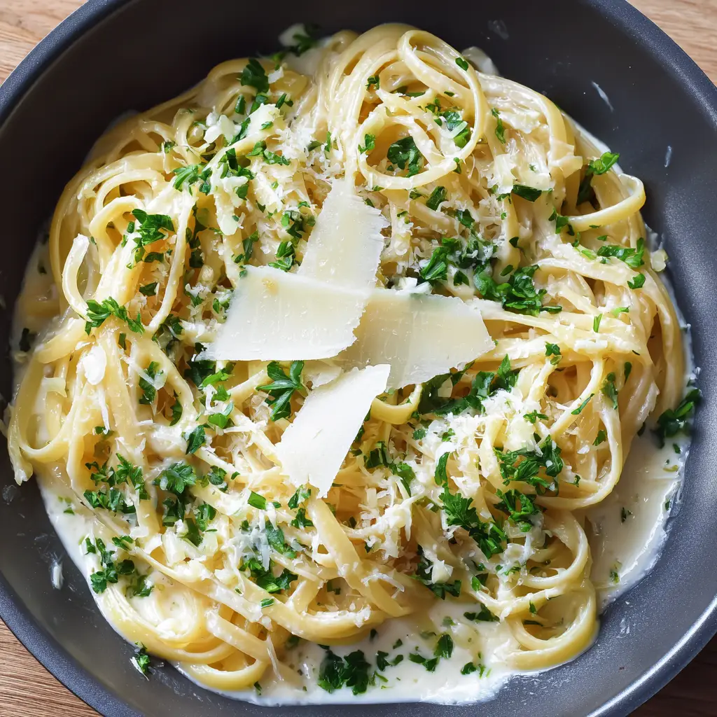Top-down shot of One Pot Creamy Garlic Pasta garnished with micro-planed parmesan and parsley.