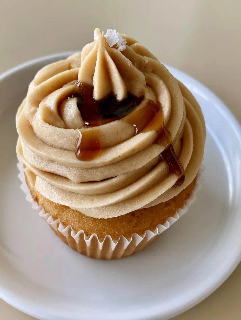 High-angle view of Maple Buttercream Frosting showing the velvety matte finish and sharp piping ridges atop a golden cupcake.