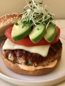 Close-up of a seared turkey patty showing green herb flecks and melted white provolone cheese. (Juicy Ground Turkey Burger Recipe)
