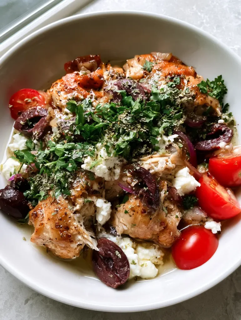 A handheld smartphone photo showing succulent shredded chicken breast and thighs with a lemon-herb glaze. (Slow Cooker Greek Chicken)
