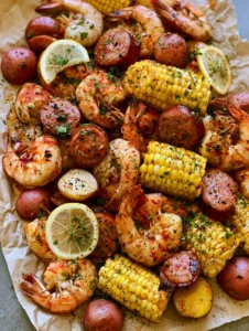 Top-down view of a Shrimp Boil Recipe with red potatoes, yellow corn rounds, and large shrimp on parchment paper.