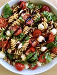 Close-up of fresh Caprese Pasta Salad showing the texture of rotini pasta and glossy balsamic drizzle.