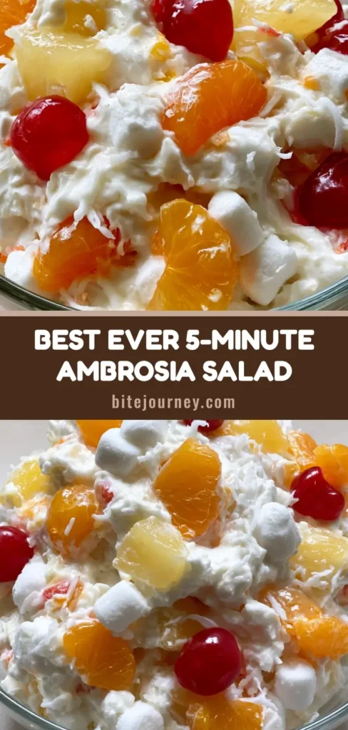 A clear glass bowl of Ambrosia Fruit Salad featuring mini marshmallows, mandarin oranges, and cherries in a thick white cream. (Ambrosia Fruit Salad)