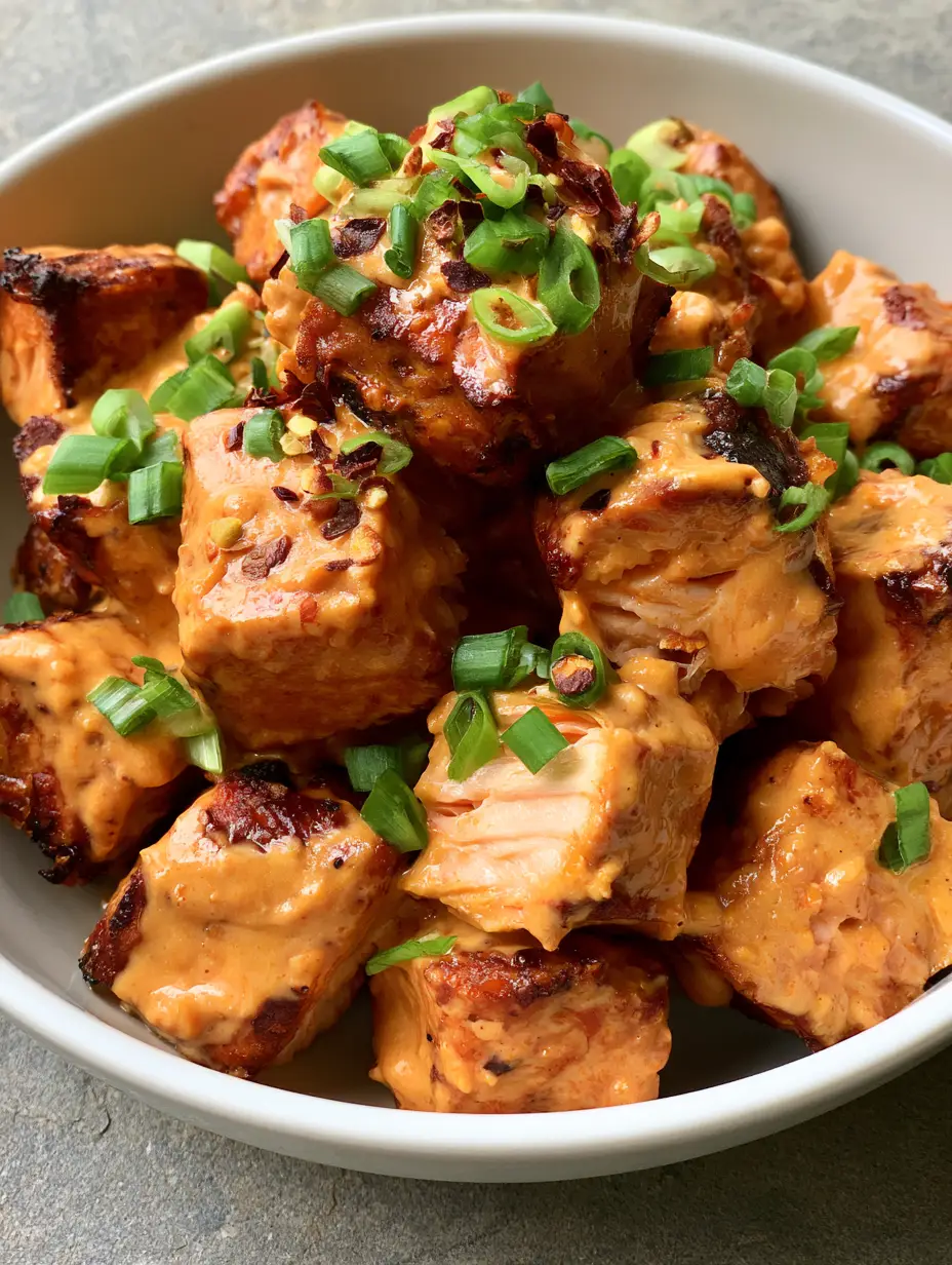 Bang Bang Salmon Bites: The Ultimate 20-Minute Crispy Appetizer 3 Close-up handheld smartphone photo of bite-sized Bang Bang Salmon Bites with glossy sauce and green onions.