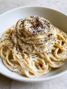 Close up of Authentic Cacio e Pepe showing the silky texture of the cheese sauce and the density of the coarse black pepper grains.