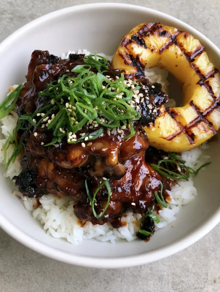 Close-up of succulent Huli Huli chicken showing the glistening glaze and grilled pineapple detail.