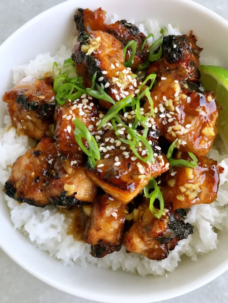 Close-up of glossy ginger lime glaze on pork with sesame seeds and green scallion garnishes.