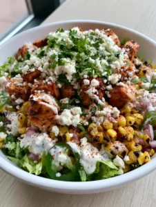 Close up of charred sweet corn and seared chicken cubes in a Chicken Street Corn Salad bowl.