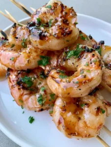 Close-up of jumbo Grilled Shrimp Skewers with visible dark brown char marks and amber honey glaze.