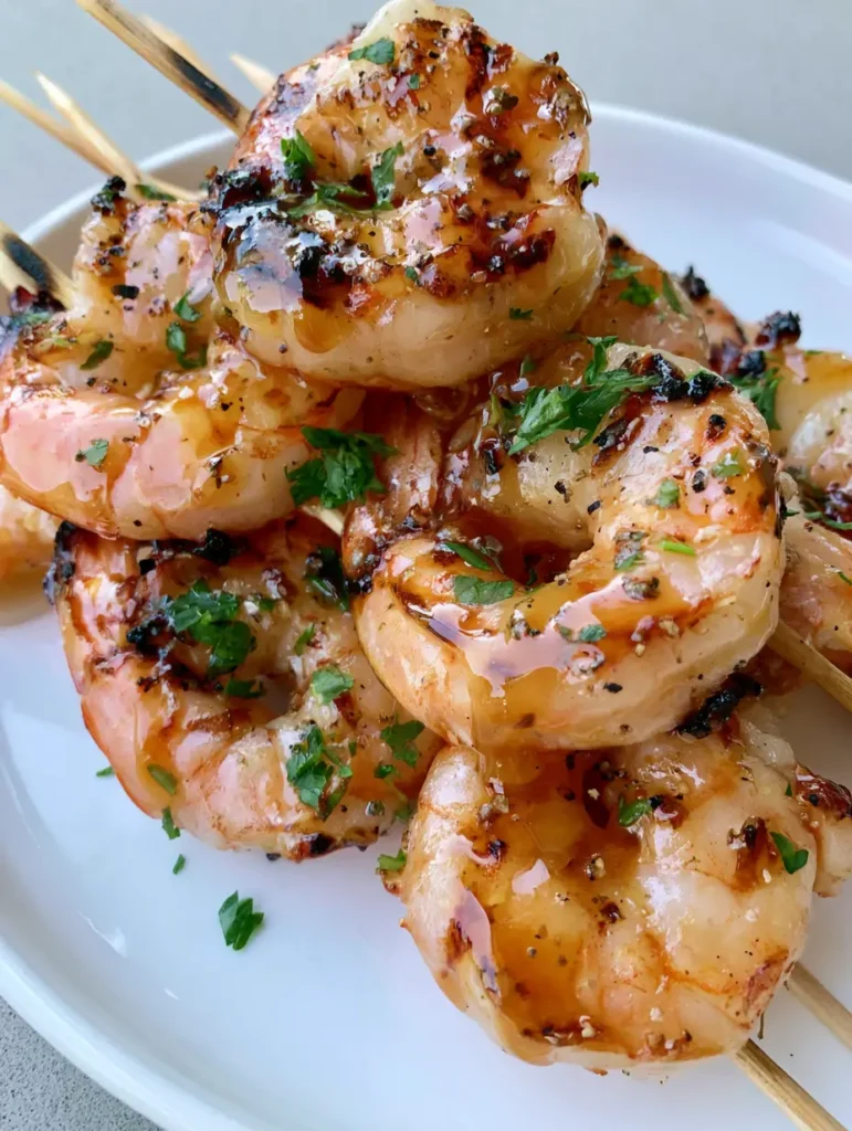 Close-up of jumbo Grilled Shrimp Skewers with visible dark brown char marks and amber honey glaze.