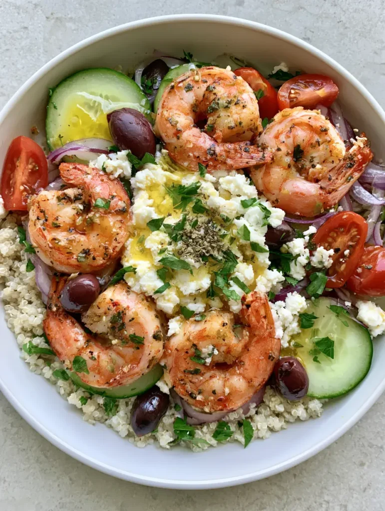 Handheld photo of a Greek Shrimp Grain Bowl on a neutral stone background.