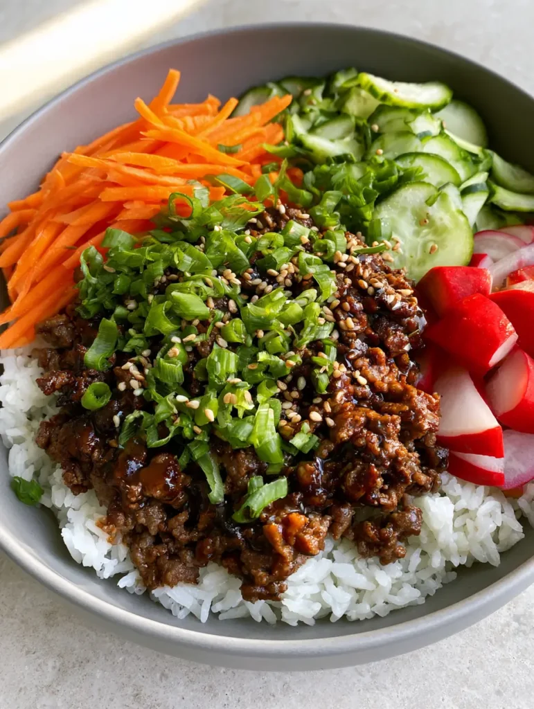 A handheld smartphone photo of Ground Beef Bulgogi Bowls showing the glossy soy glaze and vibrant vegetable sections.