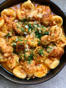 Close-up of seared chicken and plump tortellini in a glossy orange-tinted garlic butter sauce. (Spicy Garlic Butter Chicken Tortellini)