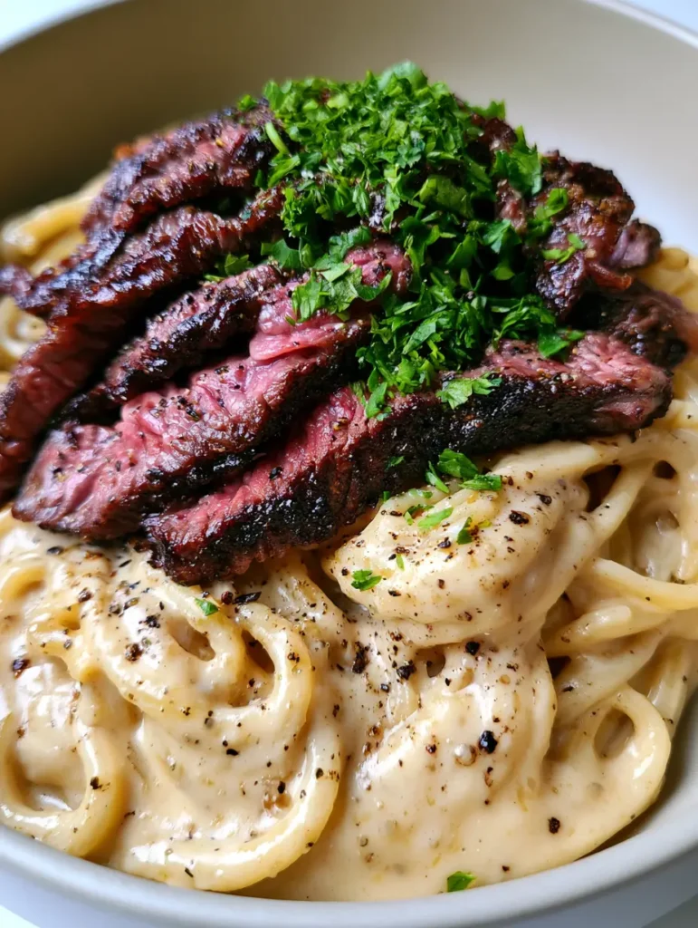 Overhead view of Creamy Steak Pasta highlighting the medium-rare pink center of the steak and fresh green parsley garnish.