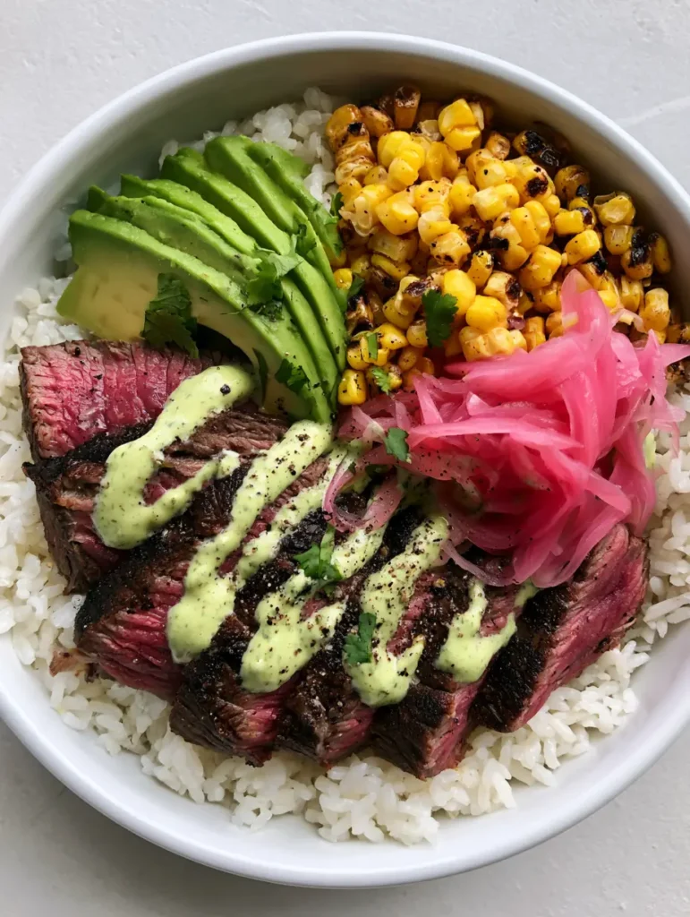 A vibrant steak and rice assembly with avocado and cilantro cream sauce.