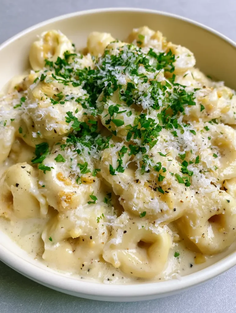 Overhead view of Creamy Garlic Butter Tortellini showing visible bits of minced garlic and bright green parsley.