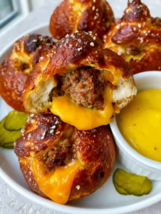 Close-up handheld photo of a glossy lye-dipped cheeseburger pretzel bomb with sesame seeds and sea salt.