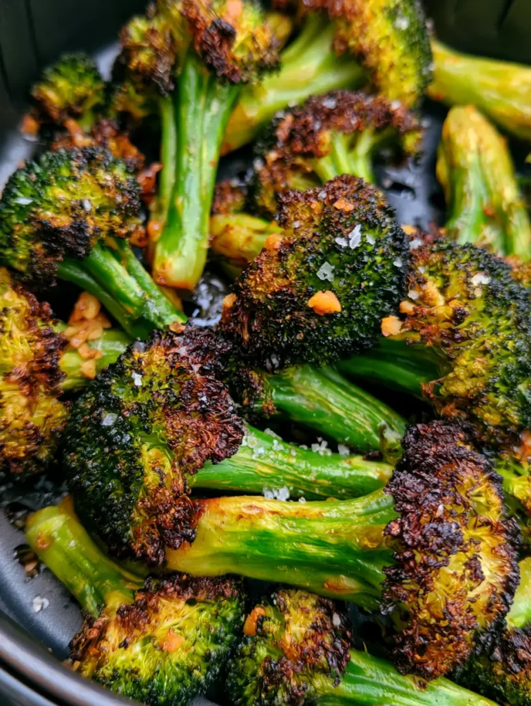 Macro shot of charred golden-brown tips on Air Fryer Broccoli florets seasoned with black pepper.